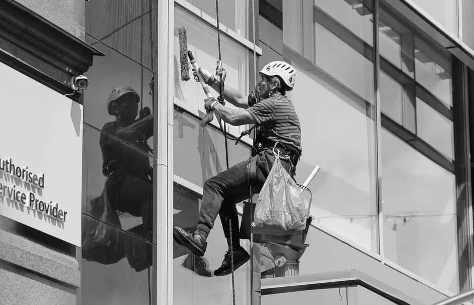 services-01 Person in PPE disinfecting indoor window area during COVID-19 pandemic.